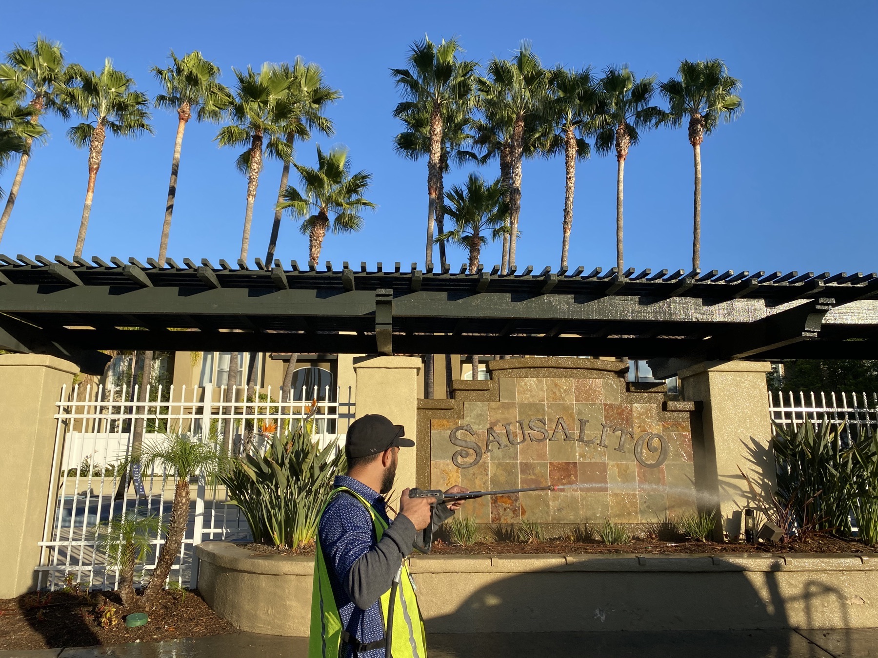 American Power Washing technician cleaning an HOA community monument sign