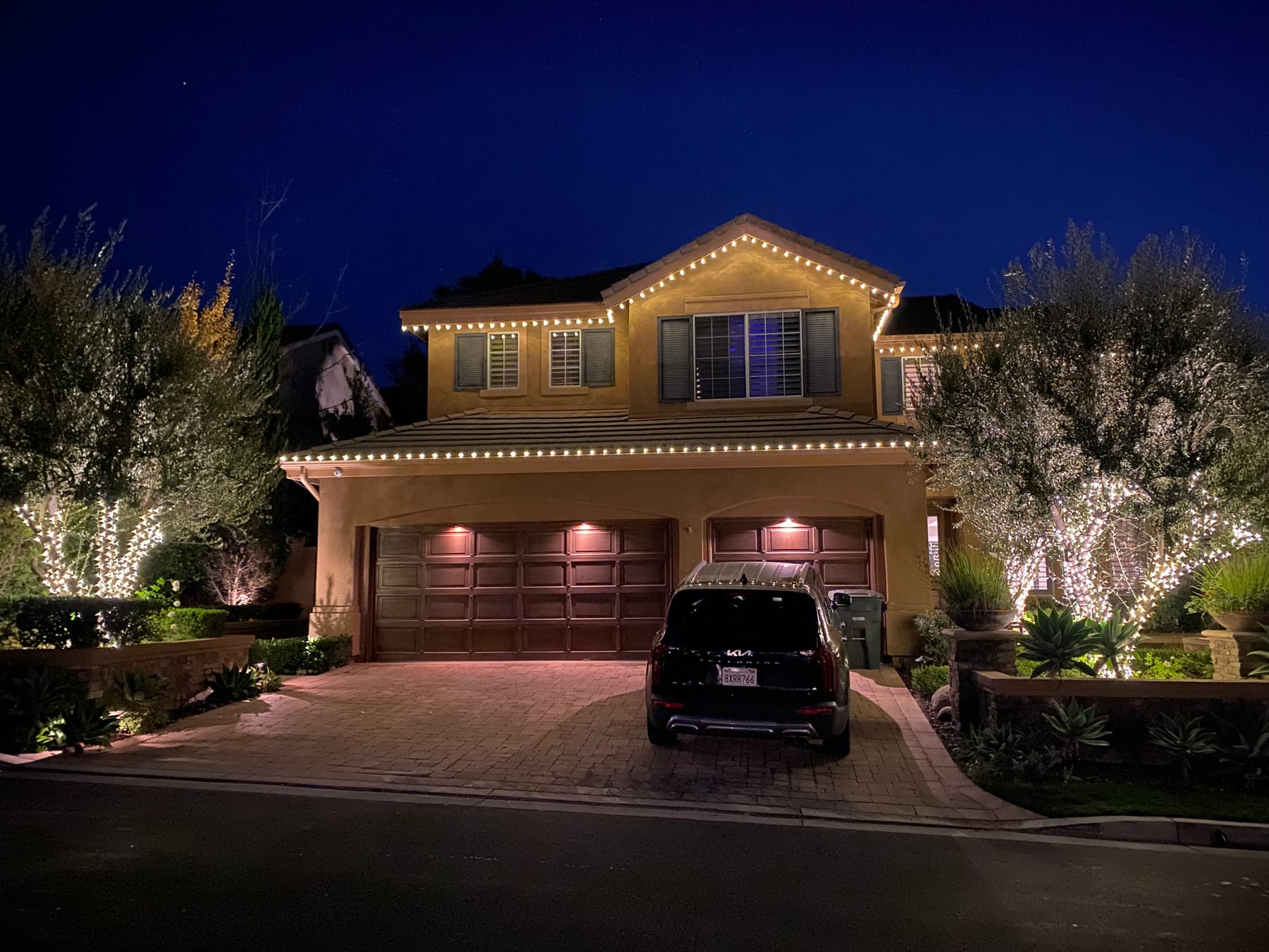 Warm white roofline and tree holiday lighting on an Orange County home